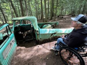Charlie is in his wheelchair beside a truck at Grant's Woods trail